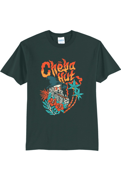 A green short-sleeved t-shirt featuring a colorful graphic on the back depicting a wizard-like figure with a long white beard, a pointed hat, sunglasses, and a pipe, surrounded by flames, hibiscus flowers, and palm trees, with the 'Cheba Hut' logo above.